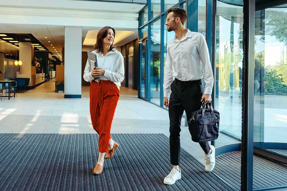 Two employees walking through a secure office lobby, representing streamlined visitor management and controlled access